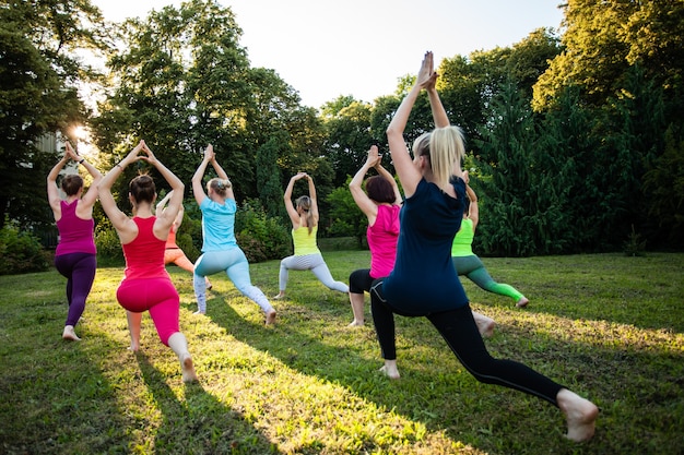 Un grupo de mujeres jóvenes atractivas deportivas practicando yoga en una naturaleza