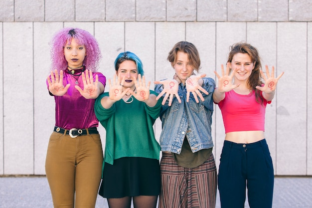 Grupo de mujeres jóvenes y de diversidad con el símbolo del feminismo escrito en sus manos.