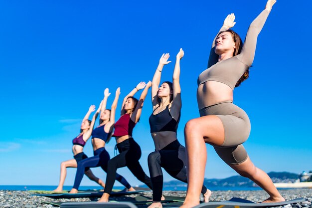 Grupo de mujeres jóvenes practicando yoga en la playa