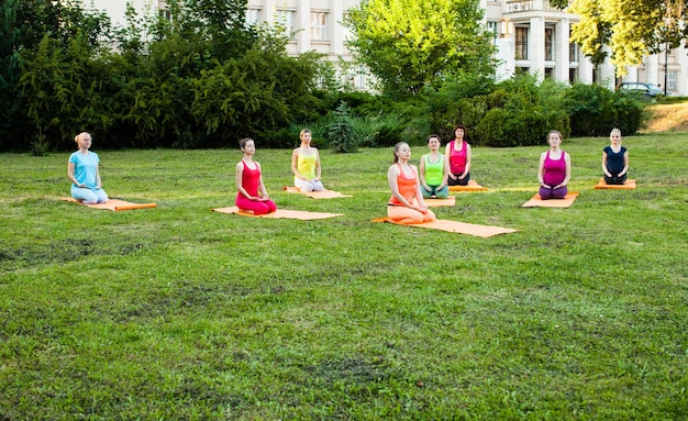 Grupo de mujeres jóvenes relajándose en un parque de la ciudad, después del entrenamiento de yoga