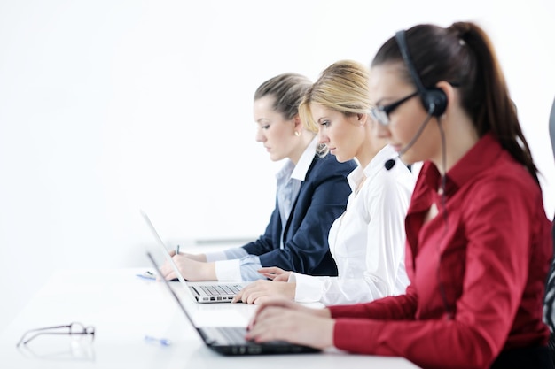 Un grupo de mujeres de negocios bastante jóvenes con auriculares sonriéndote contra el fondo blanco