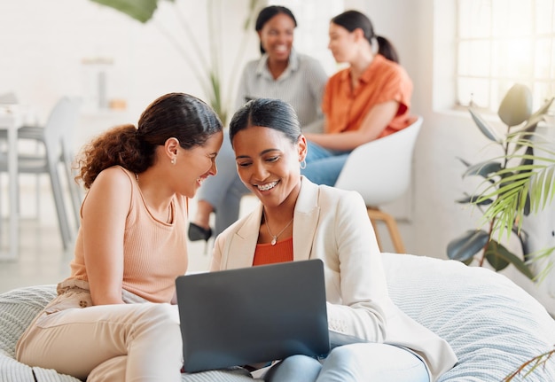 Grupo de mujeres de negocios en una computadora portátil sentadas riéndose mirando las redes sociales durante un descanso Mujeres felices uniéndose en un sofá en el trabajo Emocionado equipo de chicas celebrando el nuevo objetivo alcanzado en el inicio