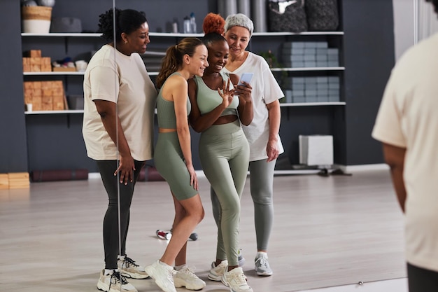 Grupo de mujeres que usan teléfonos inteligentes en el gimnasio