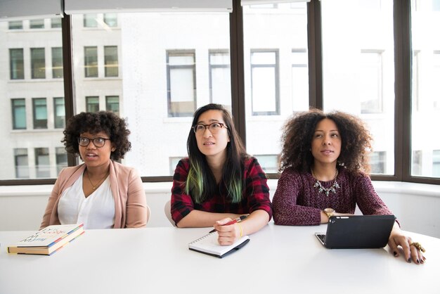 Foto un grupo de mujeres se sientan en una mesa con libros y una tiene una línea de cabello verde y negra