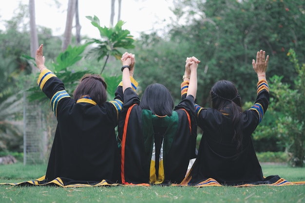 Grupo de mujeres tailandesas con vestidos de graduación sentados en el parque desde atrás.