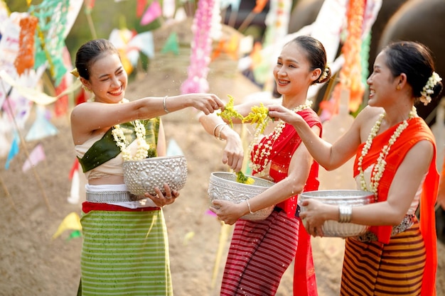 Un grupo de mujeres tailandesas con vestidos tradicionales tailandeses juegan para rociar agua el día de Año Nuevo tailandés