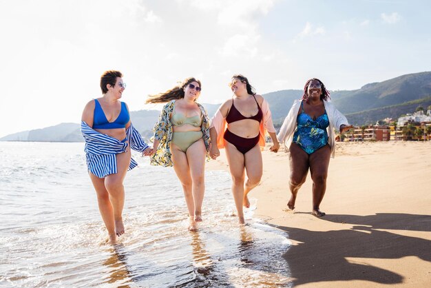 Grupo de mujeres de talla grande con traje de baño en la playa.