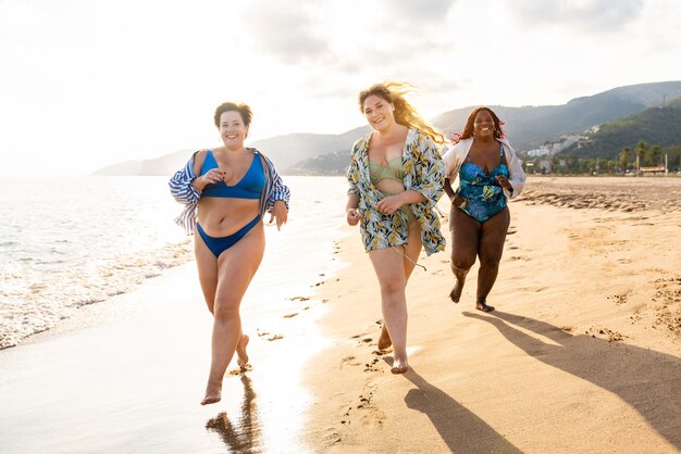 Grupo de mujeres de talla grande con traje de baño en la playa.