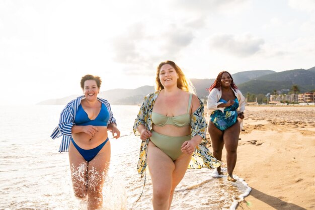 Grupo de mujeres de talla grande con traje de baño en la playa.