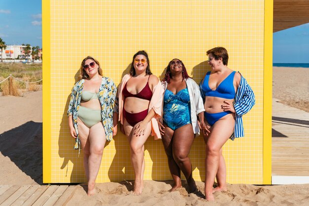 Grupo de mujeres de talla grande con traje de baño en la playa.