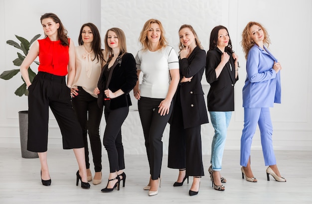 Foto un grupo de mujeres vestidas con estilo empresarial están juntas y posando para la cámara.