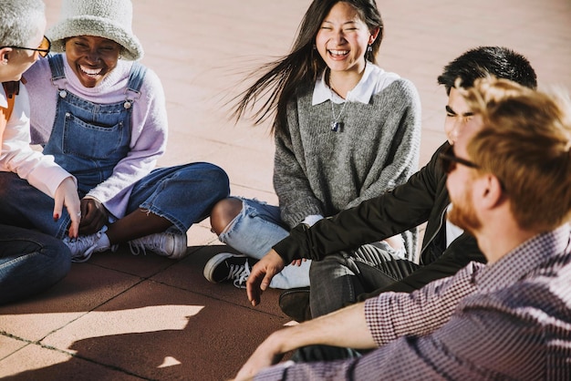 Grupo multicultural de amigos rindo juntos sentados do lado de fora