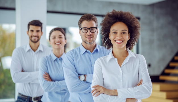 Grupo multicultural de empresários em pé com os braços cruzados em uma fileira. foco seletivo na mulher de raça mista.