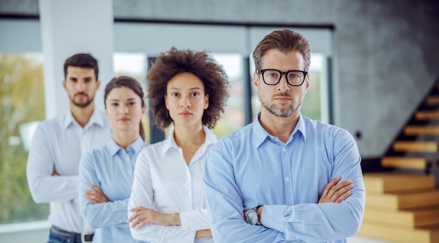 Grupo multicultural de empresários em pé com os braços cruzados em uma fileira. foco seletivo no homem em primeiro plano.