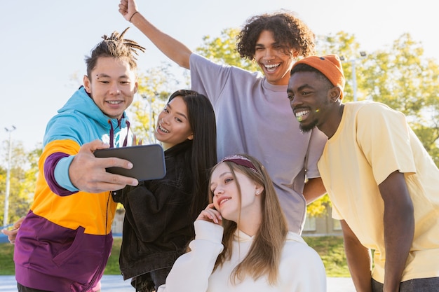 Grupo multicultural de jovens amigos se divertindo ao ar livre e se divertindo - adolescentes elegantes e descolados se reunindo no parque urbano de skate