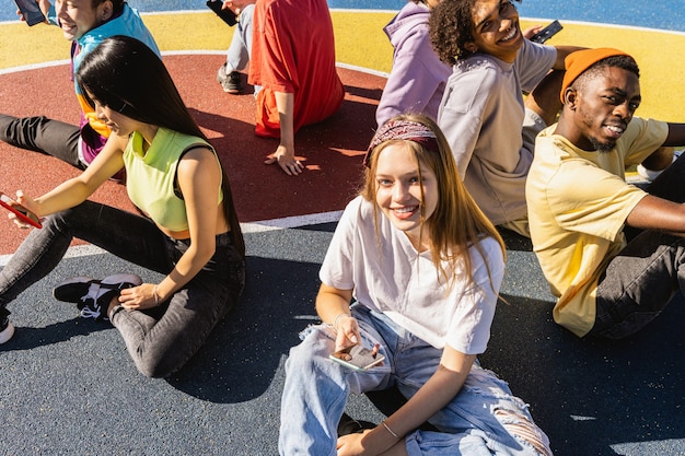Grupo multicultural de jovens amigos se divertindo ao ar livre e se divertindo - adolescentes elegantes e descolados se reunindo no parque urbano de skate
