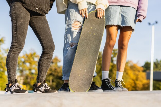 Grupo multicultural de jóvenes amigos que se unen al aire libre y se divierten - Adolescentes elegantes y geniales reunidos en un parque de patinaje urbano