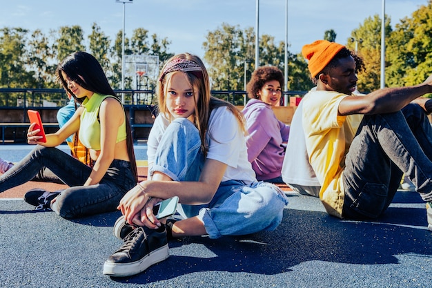 Grupo multicultural de jóvenes amigos que se unen al aire libre y se divierten - Adolescentes elegantes y geniales reunidos en un parque de patinaje urbano