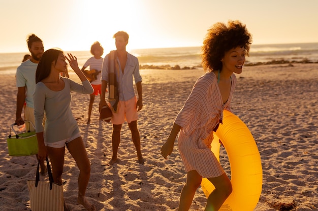 Un grupo multiétnico de amigos disfrutando de su tiempo juntos en una playa en un día soleado, caminando descalzos, hablando entre ellos
