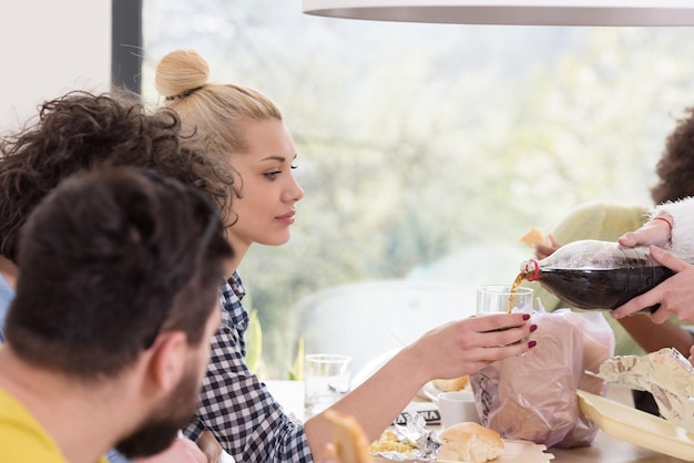 grupo multiétnico de amigos felices que pasan tiempo juntos con comida y bebidas gaseosas, comiendo en el concepto de casa