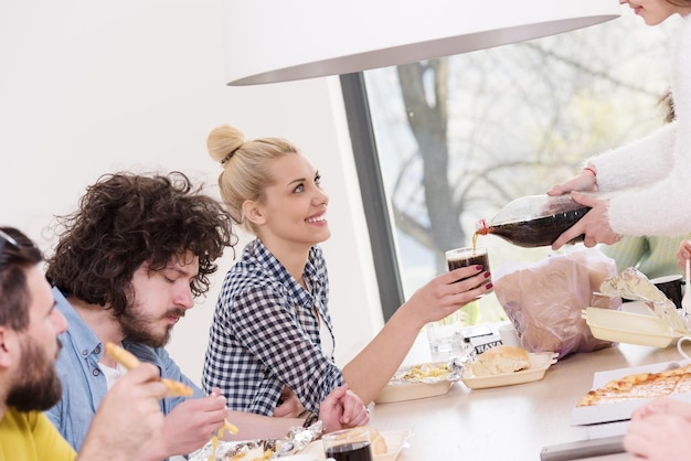 grupo multiétnico de amigos felices que pasan tiempo juntos con comida y bebidas gaseosas, comiendo en el concepto de casa