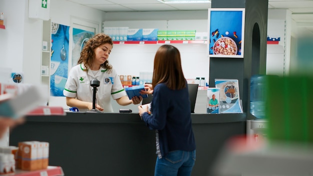 Grupo multiétnico de clientes que pagan medicamentos con tarjeta de crédito, reloj inteligente y nfc con teléfono. Gente esperando en fila para comprar productos farmacéuticos en una tienda minorista de farmacia. Disparo de trípode.