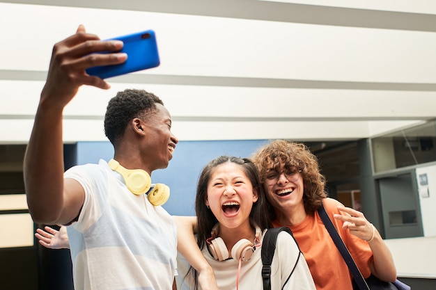 Grupo multiétnico de alunos tirando uma selfie com os colegas da faculdade se divertindo juntos