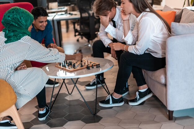 Grupo multiétnico de empresários jogando xadrez enquanto faz uma pausa na área de relaxamento no escritório de inicialização moderno. Foto de alta qualidade