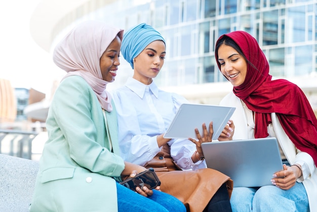 Grupo multiétnico de garotas muçulmanas vestindo roupas casuais e tradicional hijab se divertindo ao ar livre - 3 garotas árabes