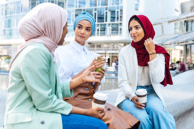 Grupo multiétnico de garotas muçulmanas vestindo roupas casuais e tradicional hijab se divertindo ao ar livre - 3 garotas árabes