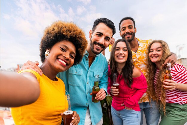 Foto grupo multiétnico de jovens amigos felizes jantando churrasco no telhado em casa