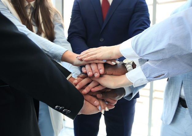 Grupo multiétnico de jovens colocando as mãos uns em cima dos outros. Feche a imagem de jovens empresários fazendo uma pilha de mãos.