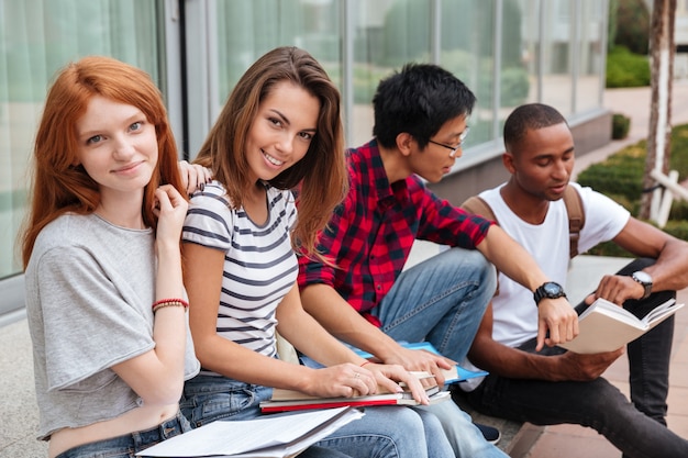 Foto grupo multiétnico de jovens estudantes felizes sentados e conversando ao ar livre