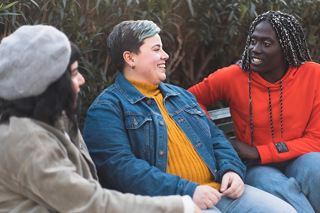 Grupo multiétnico de mulheres despreocupadas conversando juntas sentadas em um banco