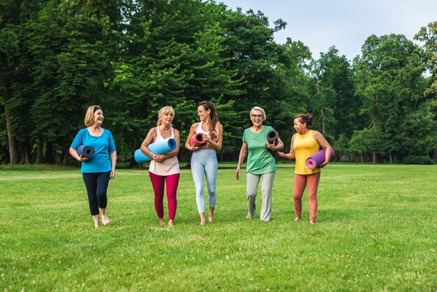 Grupo multiétnico de mulheres idosas treinando no parque com instrutor de fitness - Idosos ativos praticando esportes na natureza