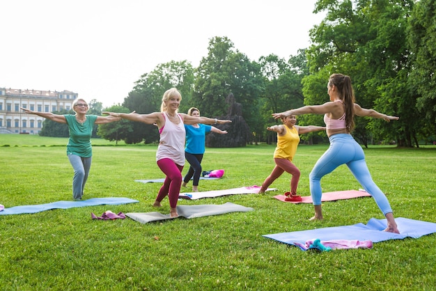 Grupo multiétnico de mulheres idosas treinando no parque com instrutor de fitness - Idosos ativos praticando esportes na natureza