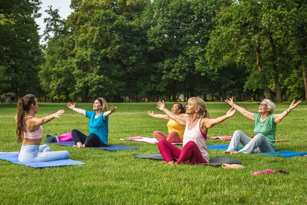 Grupo multiétnico de mulheres idosas treinando no parque com instrutor de fitness - Idosos ativos praticando esportes na natureza