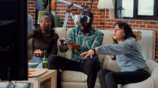 Grupo multiétnico de pessoas perdendo videogames com fone de ouvido de realidade virtual, disputando competição online no console de tv. Usando óculos 3d vr para jogar o desafio do jogo e perder, sentindo-se frustrado.