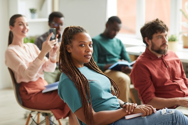 Grupo multiétnico de pessoas sentadas na platéia durante o seminário de treinamento ou conferência de negócios no escritório