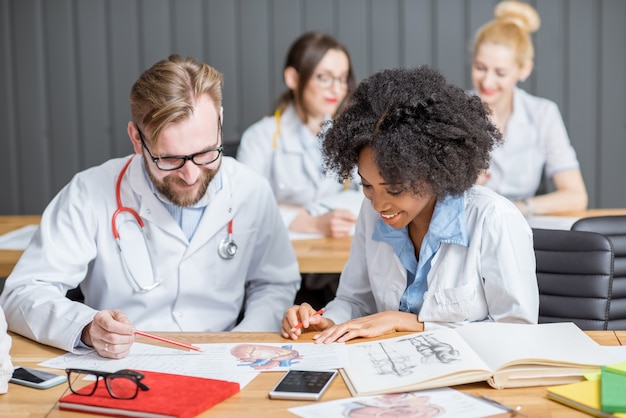 Grupo multiétnico de estudiantes de medicina en examen de escritura uniforme sentado en el aula moderna