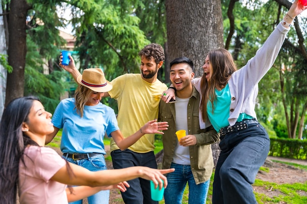 Grupo multiétnico de fiesta de cumpleaños en el parque de la ciudad abrazó divirtiéndose y bailando