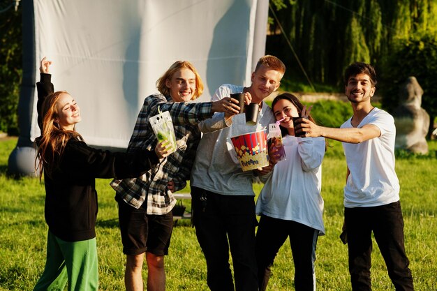 Grupo multiétnico joven de personas viendo películas en poof en cine al aire libre