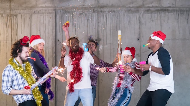 grupo multiétnico de jóvenes empresarios casuales felices bailando y teniendo una fiesta de confeti mientras celebran la víspera de año nuevo frente a un muro de hormigón en la nueva oficina de inicio