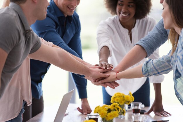 Foto grupo multiétnico de jóvenes empresarios que se ven felices mientras celebran el éxito en sus lugares de trabajo en la oficina de inicio