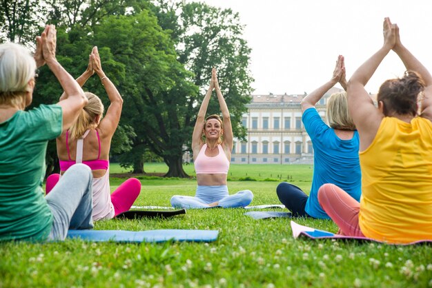 Grupo multiétnico de mujeres mayores entrenando en el parque con instructor de fitness - Ancianos activos haciendo deporte en la naturaleza