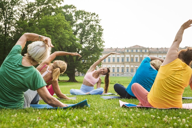 Grupo multiétnico de mujeres mayores entrenando en el parque con instructor de fitness - Ancianos activos haciendo deporte en la naturaleza