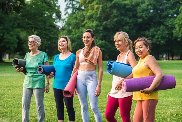 Grupo multiétnico de mujeres mayores entrenando en el parque con instructor de fitness - Ancianos activos haciendo deporte en la naturaleza