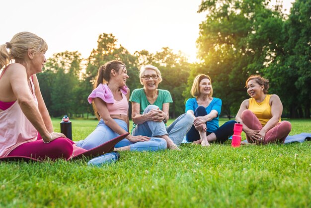 Grupo multiétnico de mujeres mayores entrenando en el parque con instructor de fitness - Ancianos activos haciendo deporte en la naturaleza