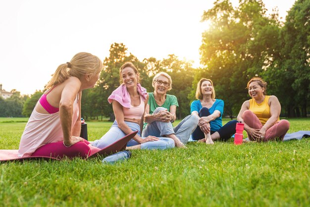 Grupo multiétnico de mujeres mayores entrenando en el parque con instructor de fitness - Ancianos activos haciendo deporte en la naturaleza