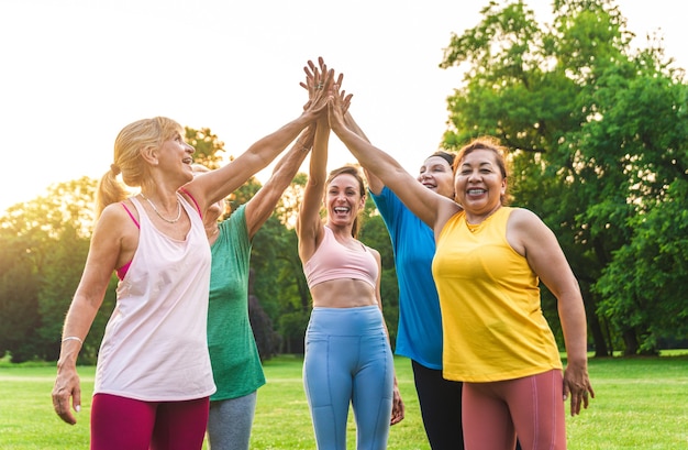 Grupo multiétnico de mujeres mayores entrenando en el parque con instructor de fitness - Ancianos activos haciendo deporte en la naturaleza